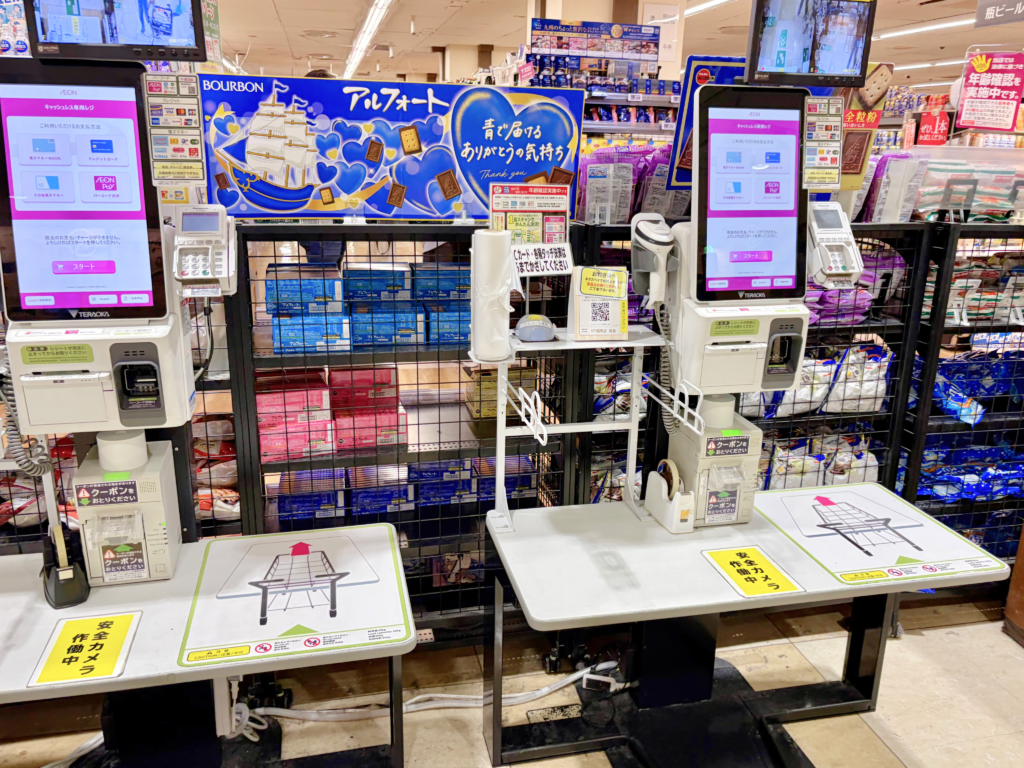 A close-up of a cashless-only self-checkout kiosk at a Japanese supermarket, displaying icons for credit cards and mobile payments with no cash slot.